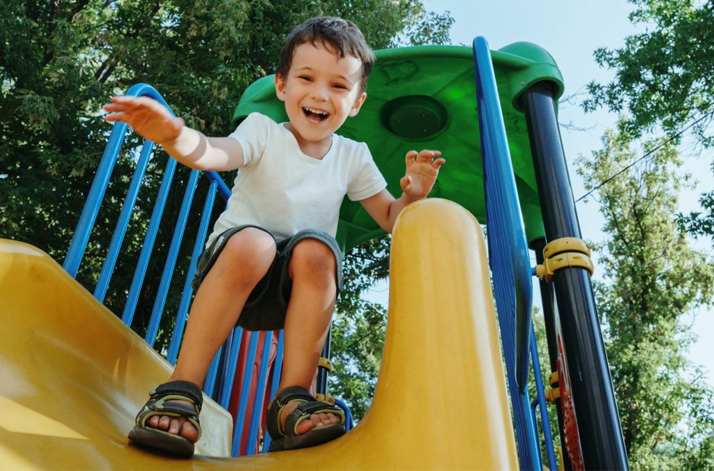Smiling boy sliding on playground, showing joyful and safe childhood moments Latattore supports